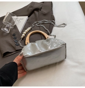Détail du sac seau plissé argenté avec poignée en bois et bandoulière perlée