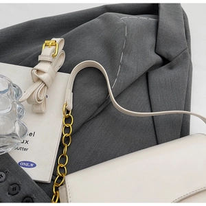 Detailopname witte lederen onderarmtas met gouden ketting en verstelbare schouderband luxe