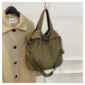 Détail du grand sac cabas vert olive avec bandoulière réglable près d'un trench-coat beige