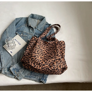 Detail of large leopard print canvas tote bag with book and denim jacket accessories