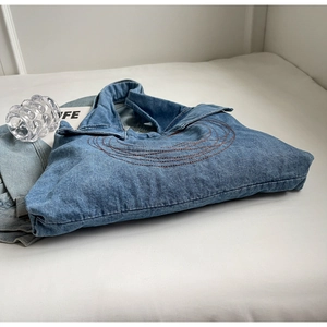 Detailed view of casual blue denim tote bag with brown embroidery on a white table