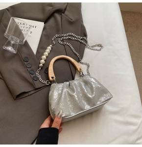 Détail du sac plissé argenté avec poignée en bois et bandoulière en perles nacrées