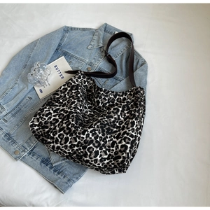 Leopard print canvas hobo bag placed over denim jacket showing texture and pattern
