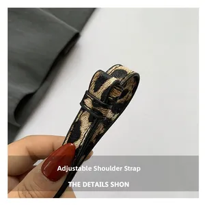 Detail of adjustable leopard print shoulder strap with black edge and metal buckle