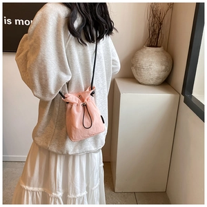 Detail view of pink nylon drawstring bucket bag with slim shoulder strap on model
