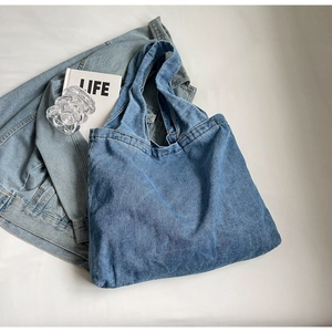 Flat lay of blue washed denim tote bag with matching jacket and lifestyle props