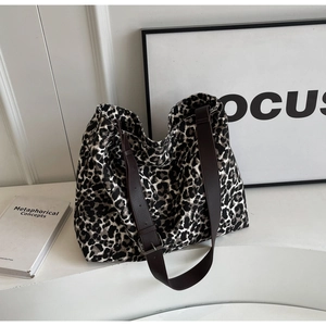 Close-up of leopard print canvas tote bag with adjustable brown leather shoulder strap