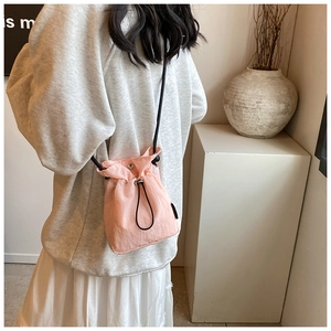 Detailed back view of a mini pink nylon drawstring crossbody bag with black rope straps