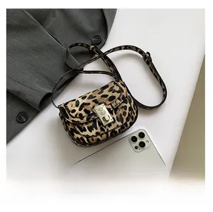 Detailed macro view of leopard print crossbody bag with metal twist lock and strap