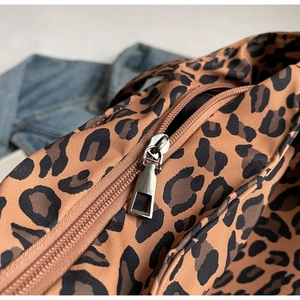 Detailed macro view of the silver metal zipper and leopard print fabric texture on a tote bag