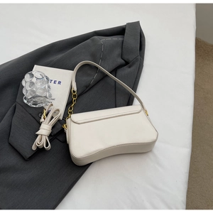 Detail van de roomwitte halvemaanvormige okseltas met gouden ketting en riem