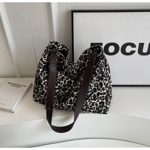Detail of leopard print canvas tote bag with brown leather strap and metal buckle