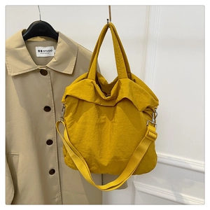 Détail d'un sac cabas jaune en nylon texturé avec crochets argentés et large bandoulière