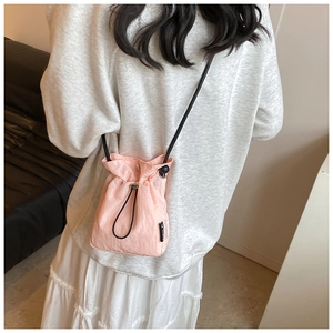 Detail view of pink nylon mini bucket bag featuring black drawstring closure and label