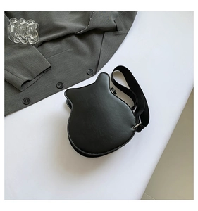 Detailed view of the black guitar-shaped matte leather crossbody bag on a gray blazer