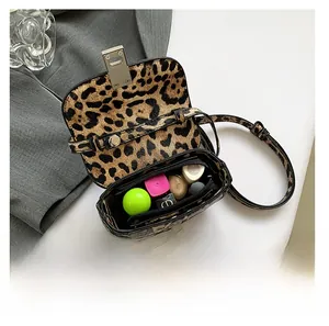 Detail view of leopard print handbag interior with silver metal clasp and small items