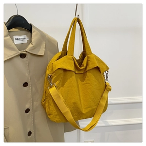 Détail d'un sac cabas en nylon jaune gingembre avec bandoulière réglable et des poignées