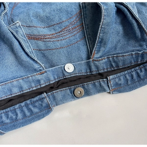 Detailed close-up of blue denim fabric with orange stitching and magnetic metal buckle