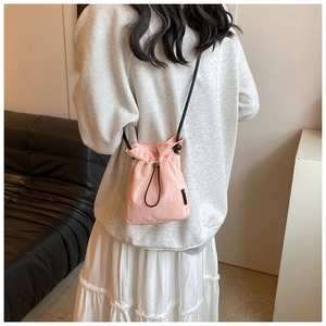 Pink drawstring crossbody bag with black shoulder strap shown on a model