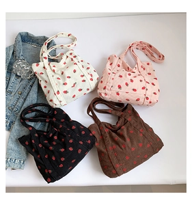 Flat lay view of four corduroy tote bags with strawberry print in white, pink, black and brown