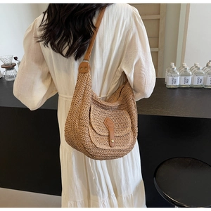 Detail der handgewebten Stroh-Schultertasche mit brauner Lederschnalle und Textur