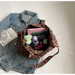 Detailed view of spacious leopard print tote bag interior holding a tablet and essentials