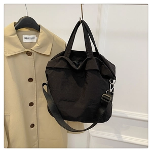 Détail du sac cabas en nylon noir avec bandoulière réglable et crochets en métal argenté