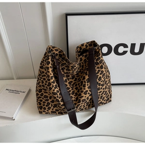Close-up of leopard print canvas tote bag with adjustable brown leather shoulder strap
