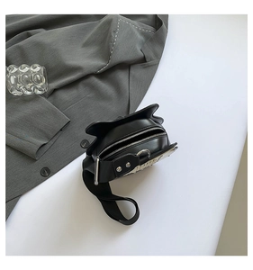 Close-up of guitar-shaped crossbody bag with wide strap and silver metal zipper detail