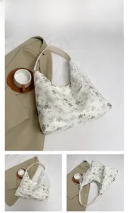 Détail du sac cabas floral vert montrant la bordure en dentelle blanche sur l'anse