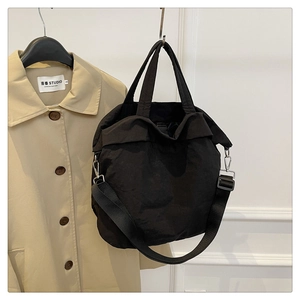 Détail du sac cabas en nylon noir avec large bandoulière tissée et boucle en métal argenté