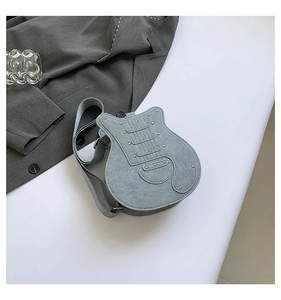 Detail of light blue guitar-shaped crossbody bag with silver studs and wide strap