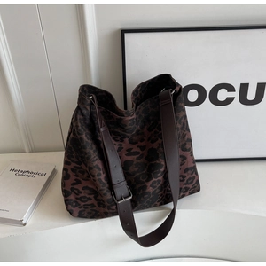 Detail of leopard print canvas tote bag featuring adjustable leather strap and twin handles