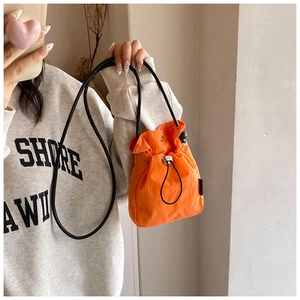 Close-up of bright orange nylon drawstring mini bag with adjustable black strap