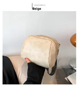 Detail der beigen Muscheltasche aus Kunstleder mit bunt gemustertem breitem Tragegurt
