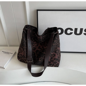 Detail of leopard print canvas bag with adjustable brown faux leather strap and buckle