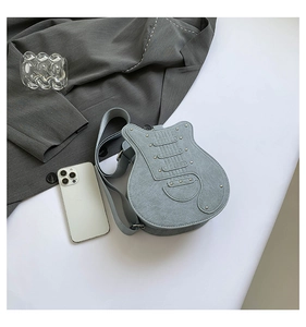 Macro view of light blue guitar shaped shoulder bag featuring suede texture and silver rivets