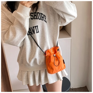Detailed shot of mini nylon drawstring crossbody bag in bright orange for women