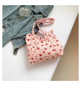 Close-up of pink corduroy tote bag featuring strawberry print and front pocket detail