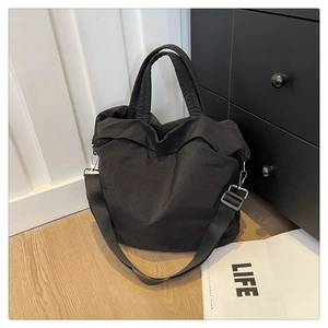 Détail du sac cabas en nylon noir avec bandoulière réglable et crochets métalliques
