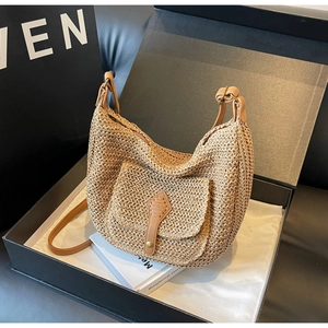 Detailansicht der Stroh-Schultertasche mit brauner Lederklappe in einer Geschenkbox
