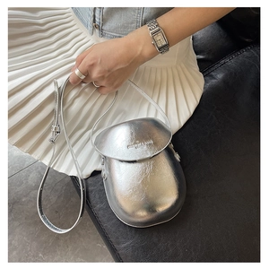 Detail of silver metallic textured crossbody bag with fashion logo and thin shoulder strap
