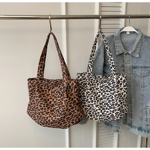 Detailed view of two leopard print canvas tote bags hanging with wide shoulder straps