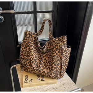 Dettaglio ravvicinato della borsa tote in tela leopardata con tasca laterale su pietra