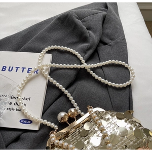 Detail of golden sequin evening clutch with pearl clasps and long pearl chain strap
