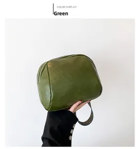 Detailansicht der dunkelgrünen Muscheltasche mit Ölwachstextur und Ethno-Gurtband