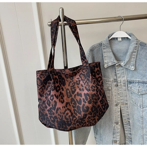 Detail shot of large capacity leopard print tote bag hanging with denim jacket