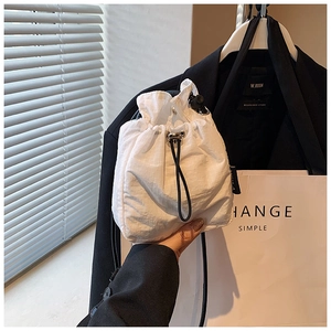 Detail of white nylon mini drawstring bag with silver eyelets and black adjustable strap