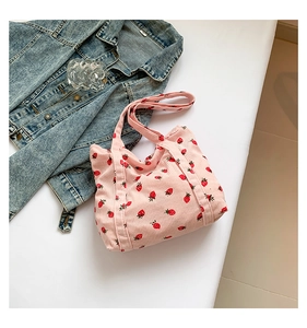 Detail of pink corduroy tote bag with strawberry print and soft ribbed texture