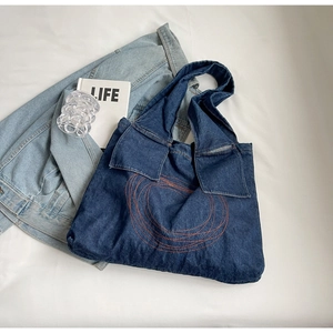 Detail of blue denim tote bag with orange contrast stitching and stylish collar-style flap